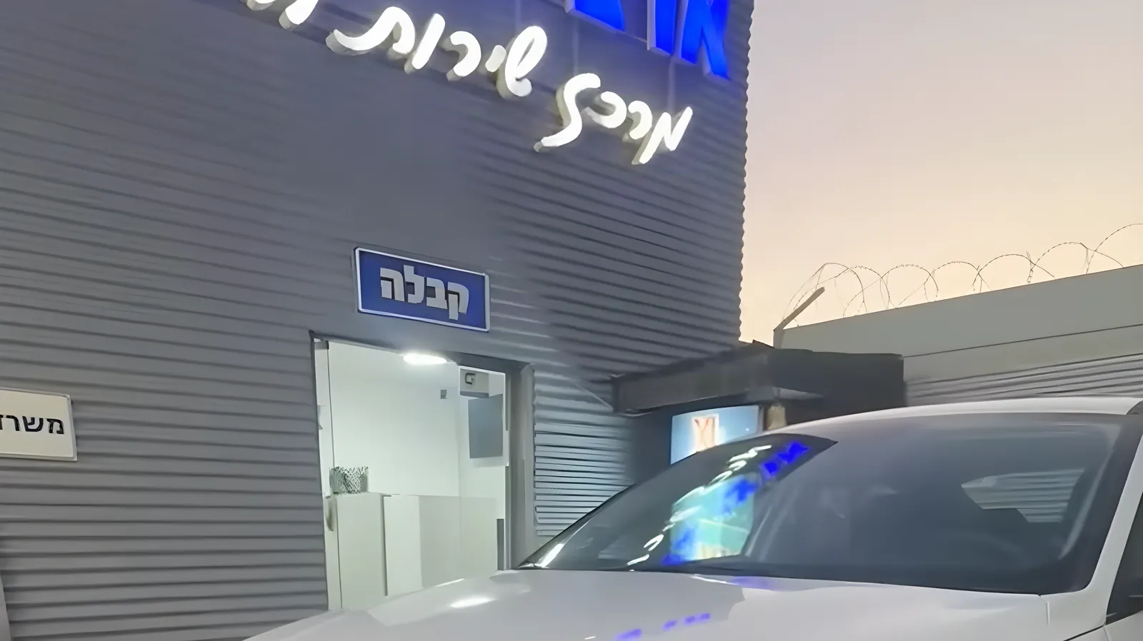 בניין המוסך בערב, השלט מרכז שירות לרכב מואר והכניסה לקבלה