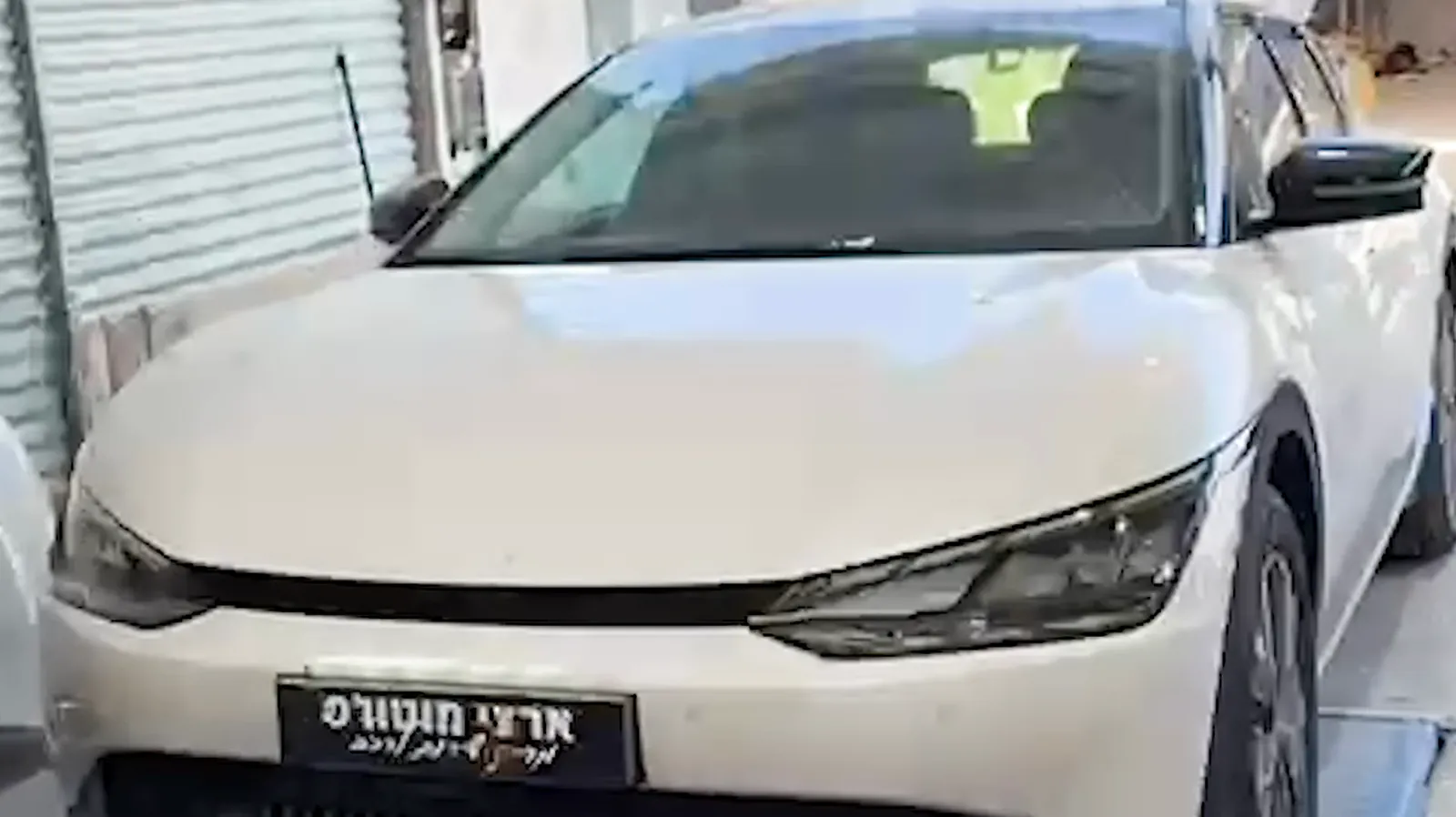 רכב לבן מוכן על המעמד אחרי טיפול, עם לוחית של ארצי מוטורס